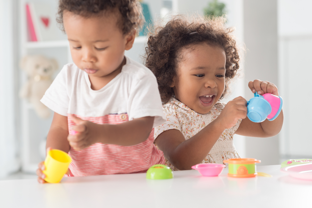 Close-up image of cheerful little girl playing with toys with her brother on the foreground